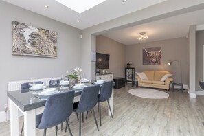 Uma sala de estar moderna com área de jantar, sofá e televisão de tela plana na parede.