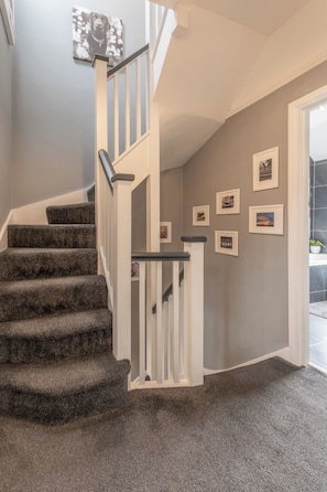 A staircase with carpeted steps and white railings, leading to a landing with a door.
