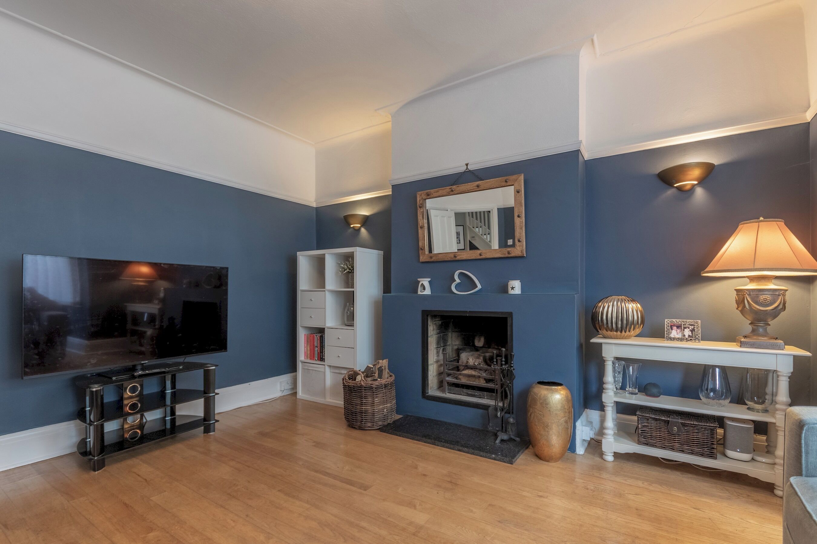 A living room with a flat-screen TV, a fireplace, and a lamp.