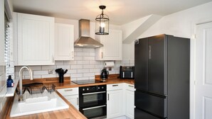 Una cocina moderna con armarios blancos, un refrigerador negro y una encimera de madera.