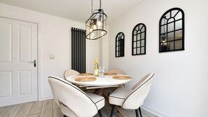 Comedor con una mesa redonda, cuatro sillas, una lámpara colgante y tres ventanales de arco.