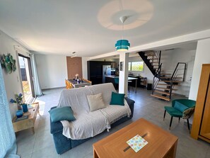 Ein modernes Wohnzimmer mit einer Couch, einem Couchtisch und einer Treppe, die in einen oberen Bereich führt.