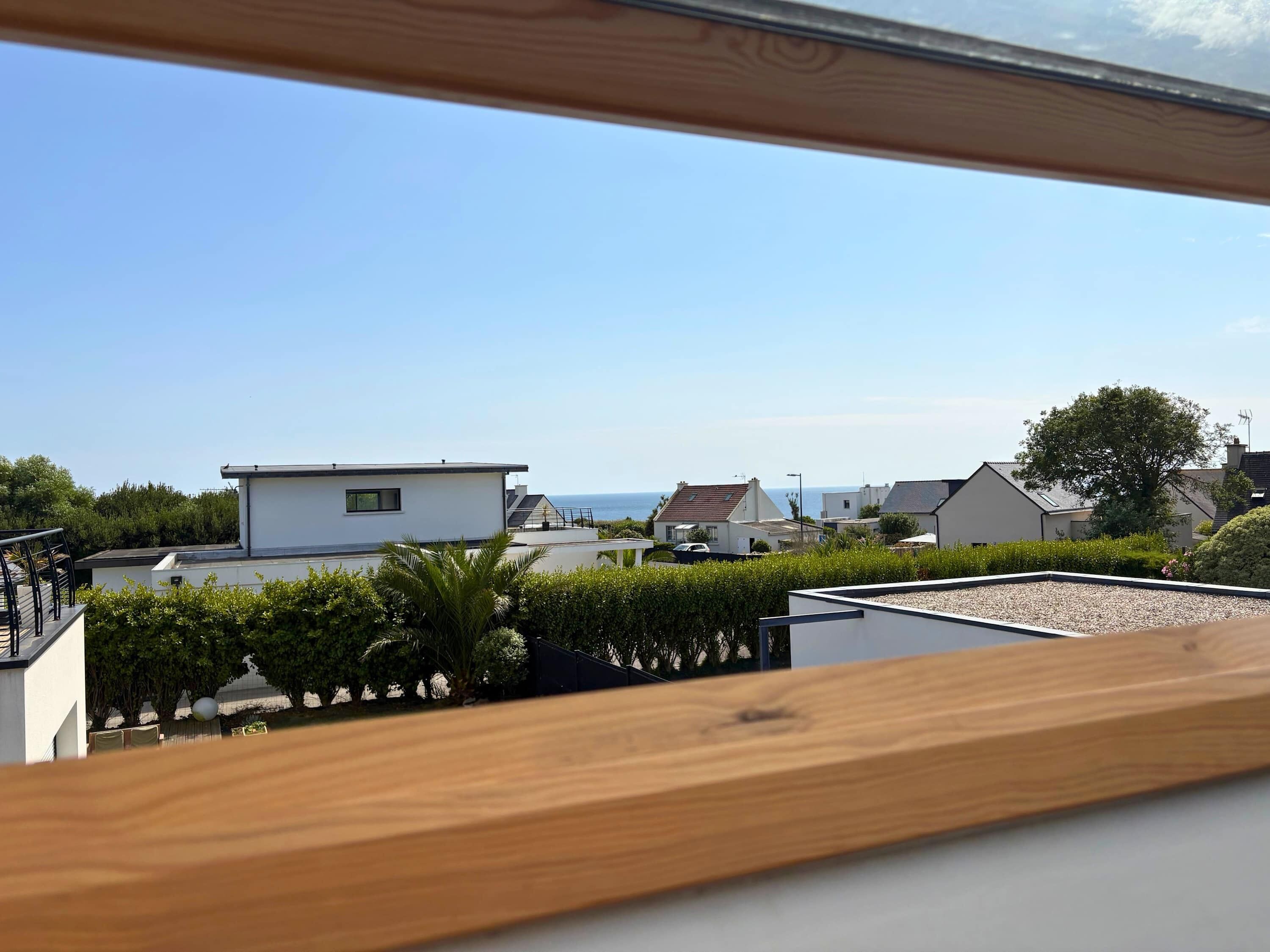 A residential area with modern houses, a clear sky, and a view of the sea.