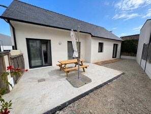 A modern house with a patio, a wooden table, and a covered area. - KER MOAN, New house for a family in town centre (Milizac-Guipronvel)