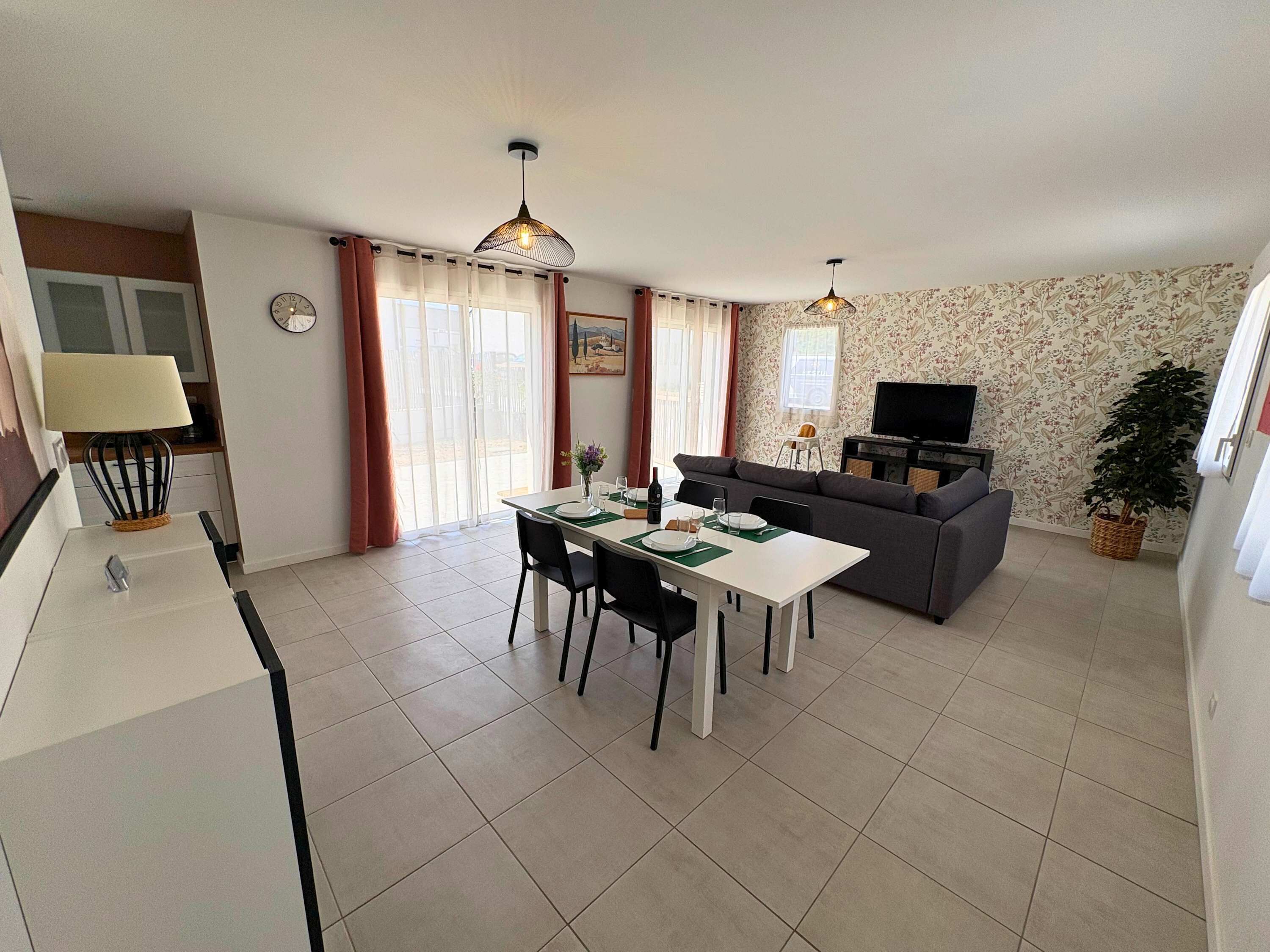 A modern living room with a dining area, a sofa, a TV, and a plant.