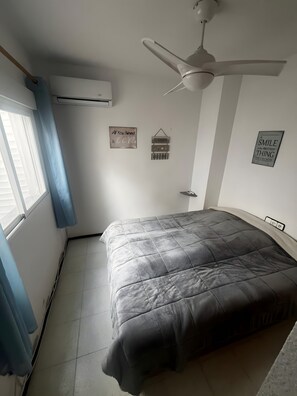 Une chambre à coucher comprenant un lit, un ventilateur de plafond, un appareil de climatisation et des éléments décoratifs sur les murs.