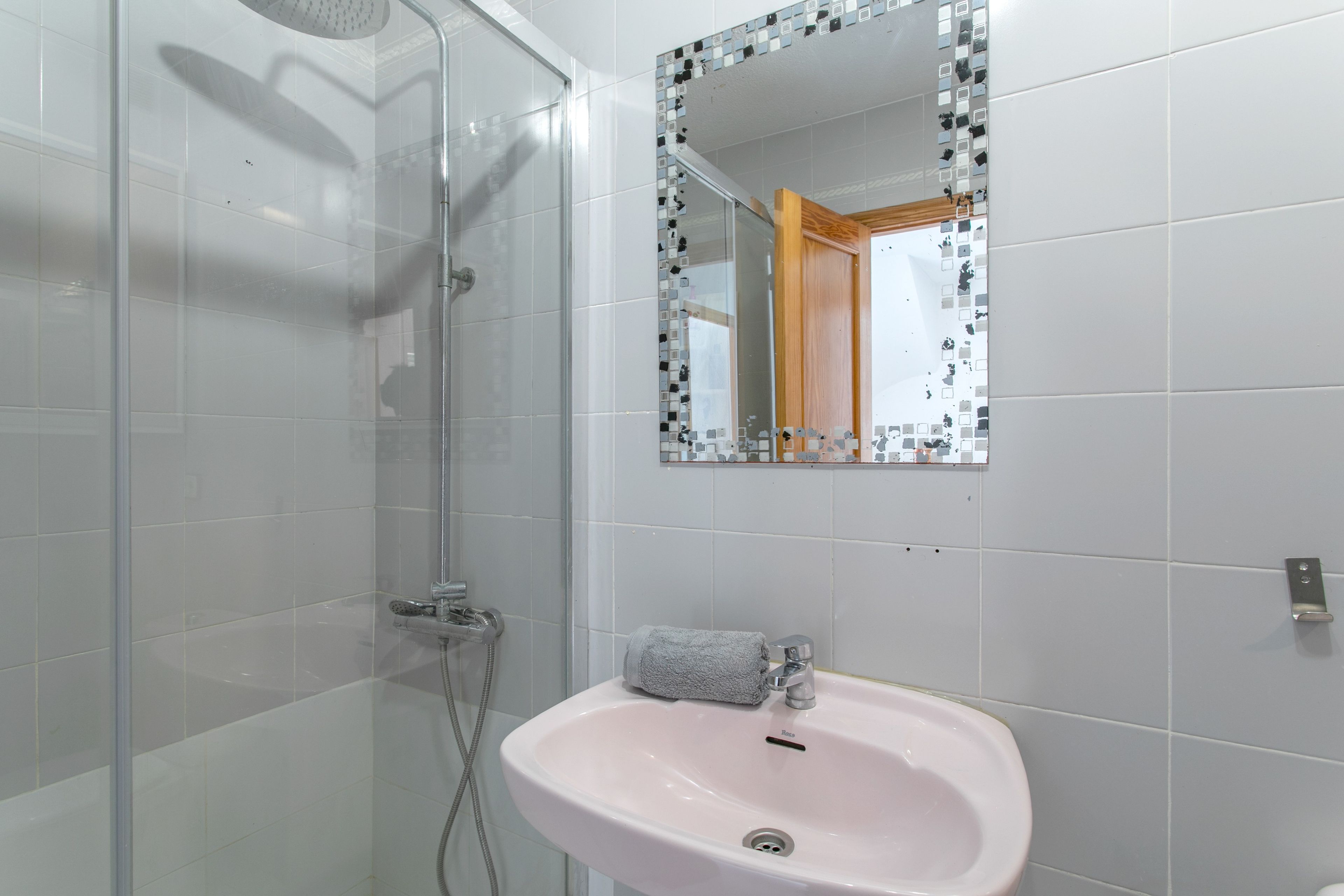 Ein Badezimmer mit Dusche, Waschbecken und Spiegel.