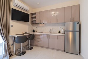 A modern kitchen with a built-in refrigerator, a sink, and two bar stools. - SnJ Studio No2 by RentalsPro - Nea Flogita Halkidiki (Nea Flogita)
