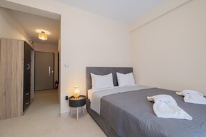 A hotel room with a bed, bedside table, and a wardrobe. - SnJ Studio No2 by RentalsPro - Nea Flogita Halkidiki (Nea Flogita)