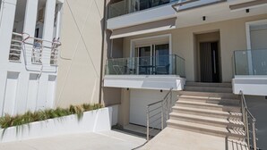 Un immeuble résidentiel à plusieurs étages, doté de balcons, d’un escalier et d’une entrée fermée par un portail.