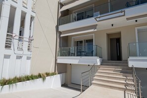 A multi-story residential building with balconies, a staircase, and a gated entrance. - SnJ Studio No1 by RentalsPro - Nea Flogita Halkidiki (Nea Flogita)