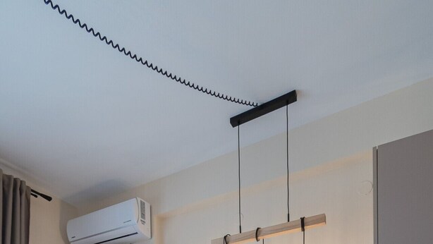 Une cuisine moderne dotée d’un réfrigérateur encastré, d’un téléviseur à écran plat et de luminaires suspendus.