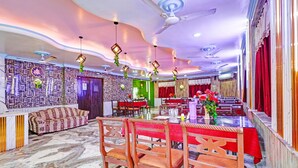 A dining area with a high ceiling, patterned walls, and a seating arrangement with tables and chairs. - Classic Hotel Bidisha (Kanthi)