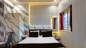 A hotel room with a large bed, a chair, a desk with a telephone, and a window with curtains. - Classic Hotel Bidisha (Kanthi)