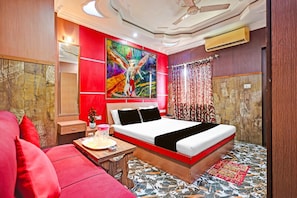 A hotel room with a bed, a desk, a chair, and a large painting on the wall.