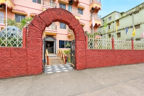 A building entrance with a red textured archway, a gated pathway, and a tiled floor. - Classic Hotel Bidisha (Kanthi)