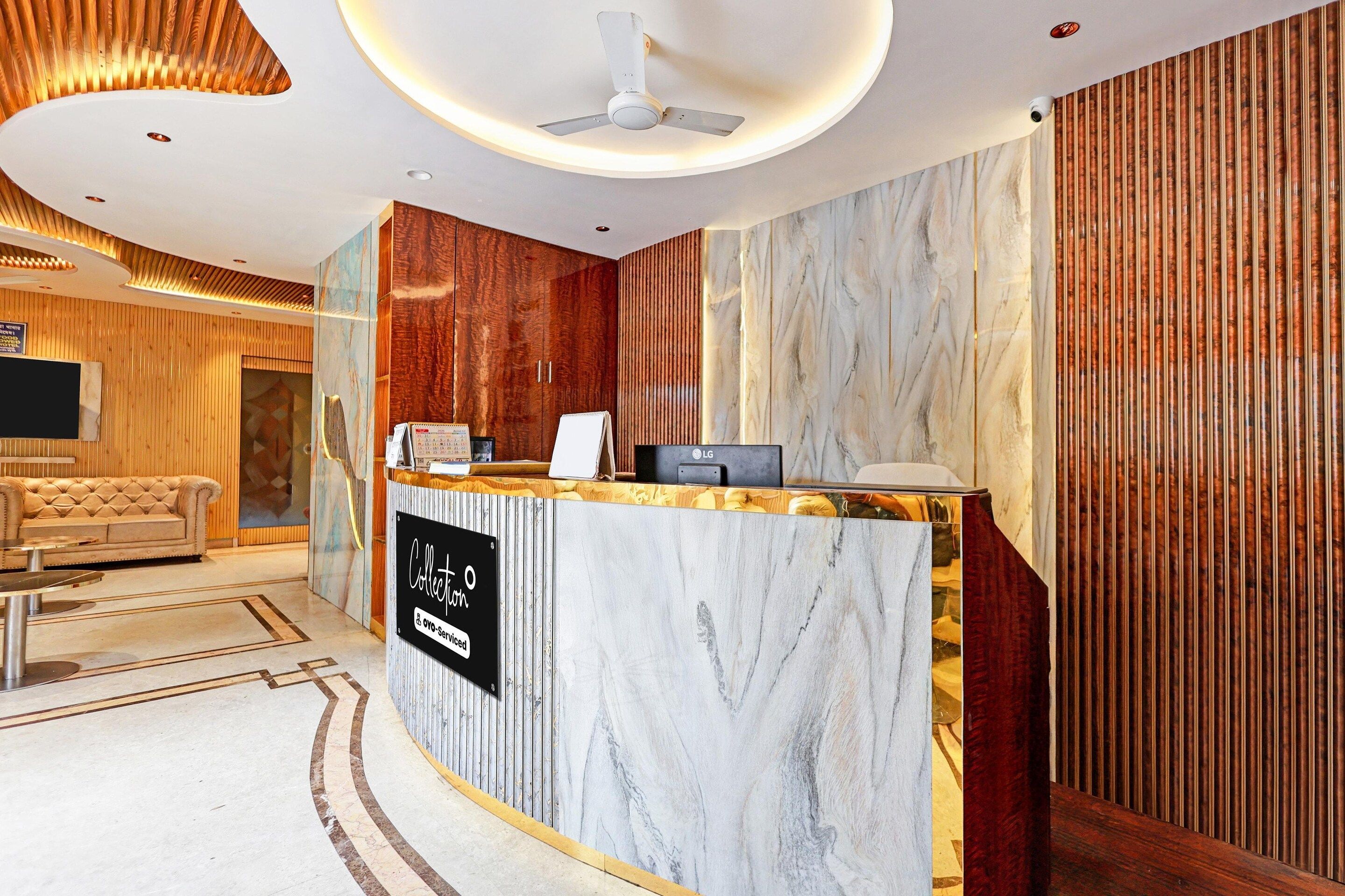 A hotel reception area with a marble counter, a ceiling fan, and a wooden wall.