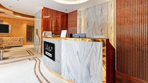 A hotel reception area with a marble counter, a ceiling fan, and a wooden wall. - Classic Hotel Bidisha (Kanthi)