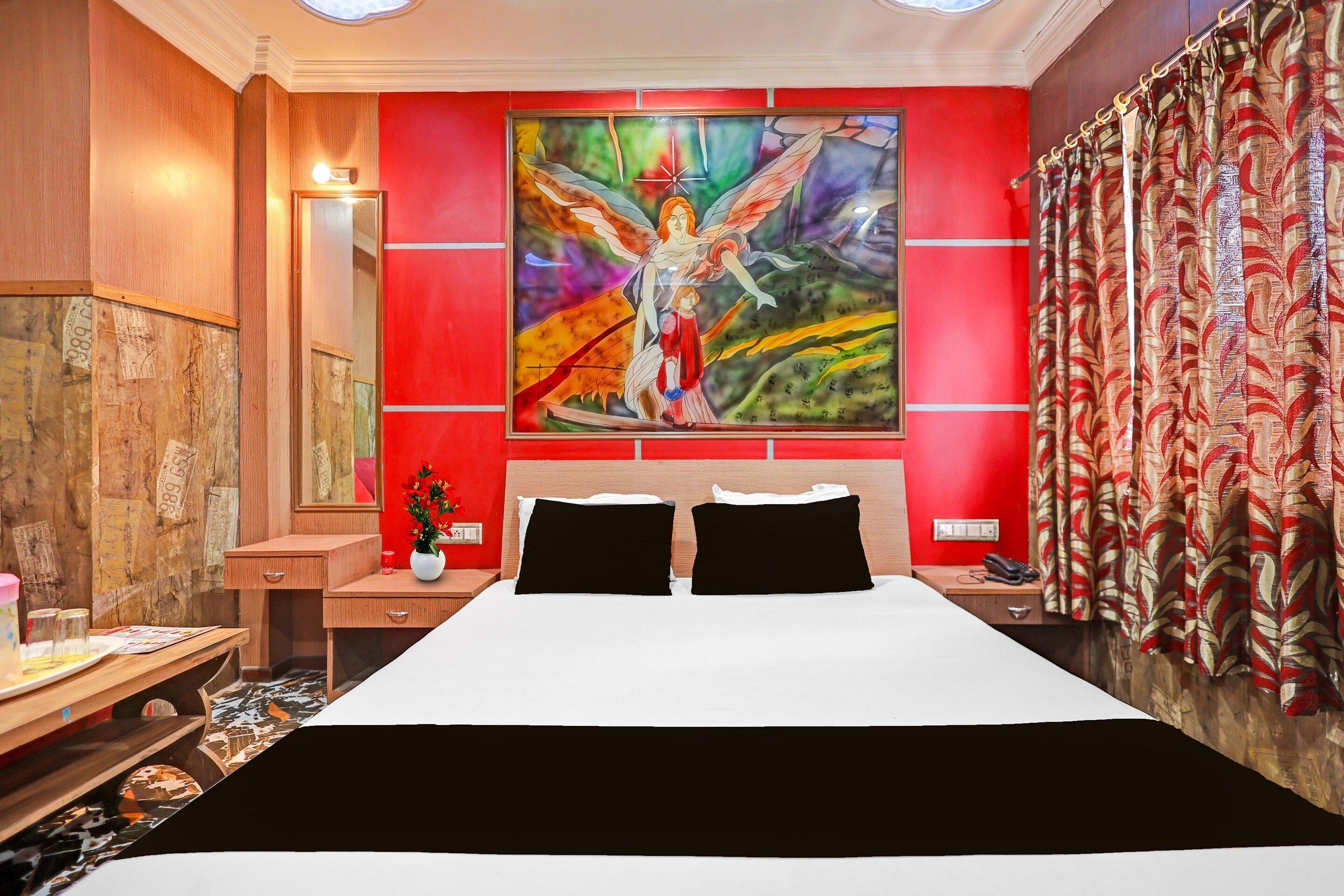 Une chambre d’hôtel avec un grand lit, une table de chevet, un bureau et un tableau au mur.