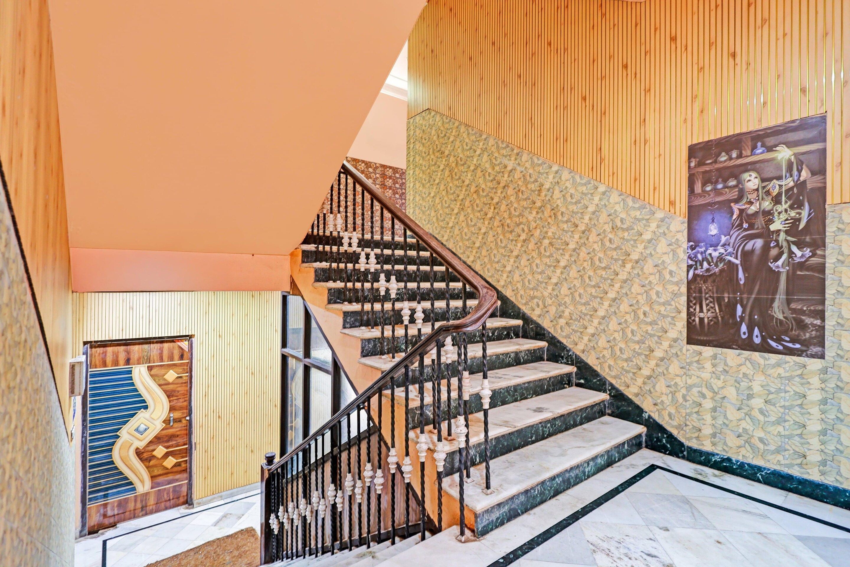 A staircase with a wooden handrail and black balusters, leading to a room with a patterned wall and a poster.