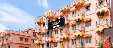 A multi-story building with balconies and a sign indicating it is serviced by OYO.