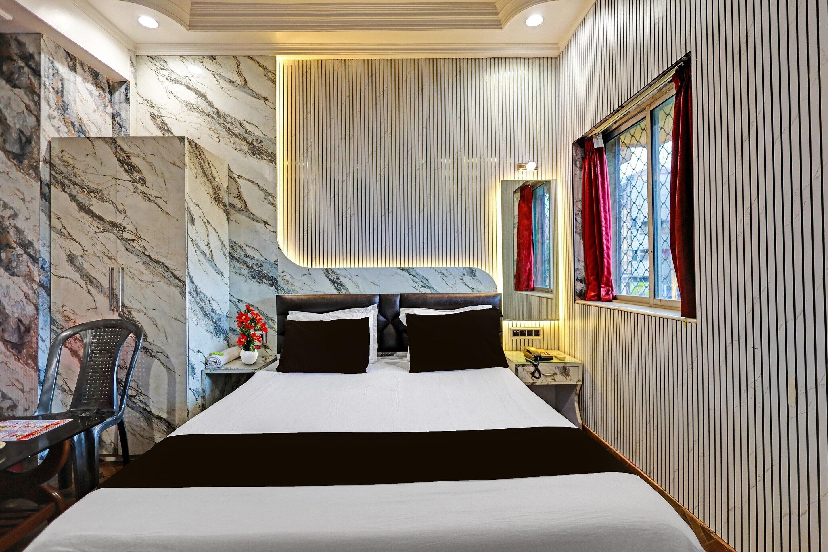 Habitación de hotel con una cama grande, una silla, un escritorio con teléfono y una ventana con cortinas.