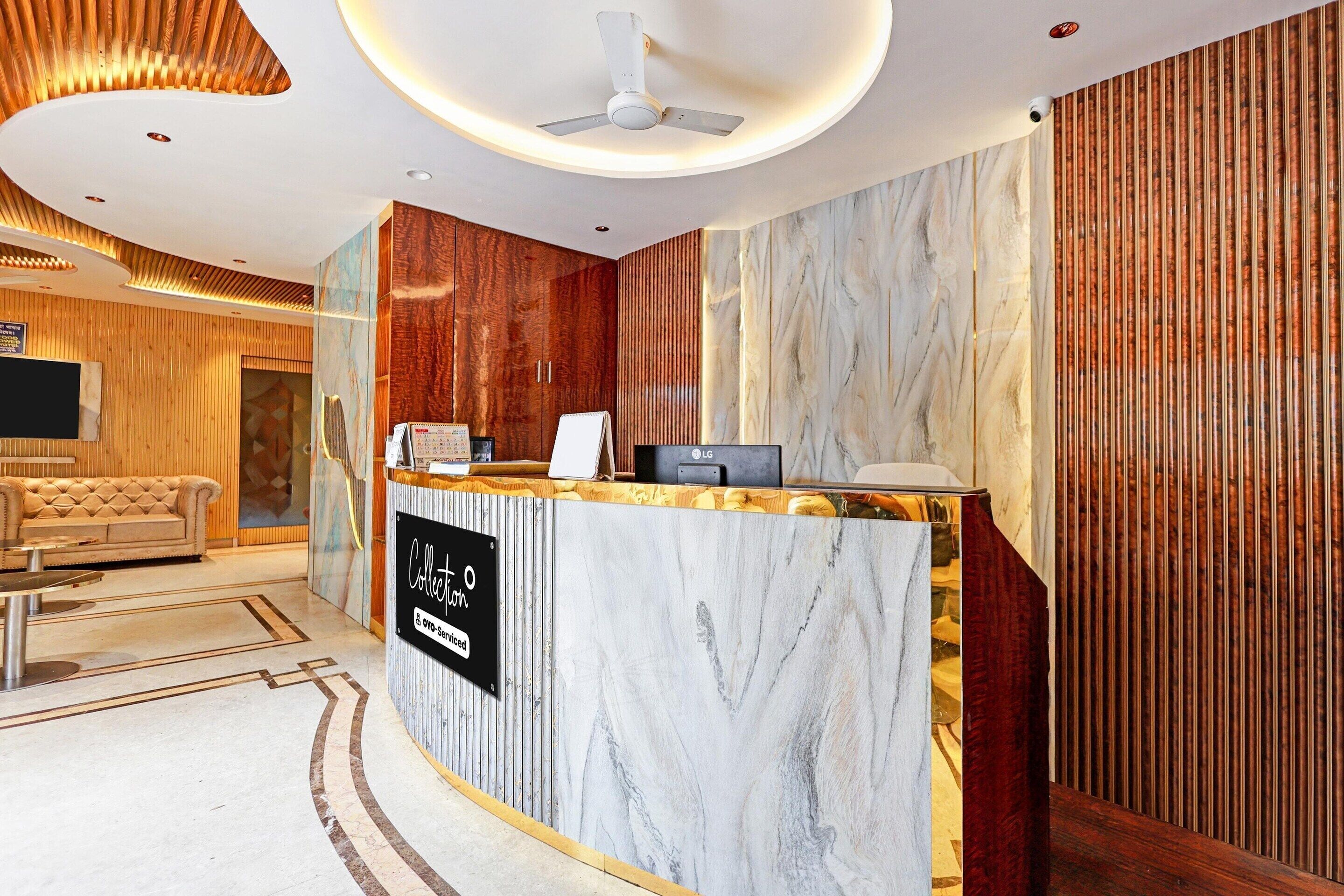 A hotel reception area with a marble counter, a ceiling fan, and a wooden wall.