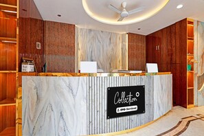 A reception desk with a marble countertop, a sign reading 'Collection OYO-Serviced', and a ceiling fan. - Classic Hotel Bidisha (Kanthi)