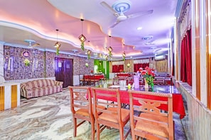 Un comedor con techos altos, paredes con diseño y una disposición de mesas y sillas.