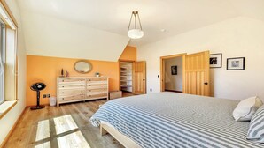 Ein Schlafzimmer mit Bett, Kommode und begehbarem Kleiderschrank.