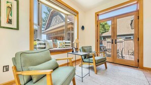 A room with a large sliding glass door leading to an outdoor patio, a sofa, a small table, and a chair. - Pelican Perch by Manzanita Beach Getaway- Walk to Beach & Downtown, Dog-Friendly (Manzanita)