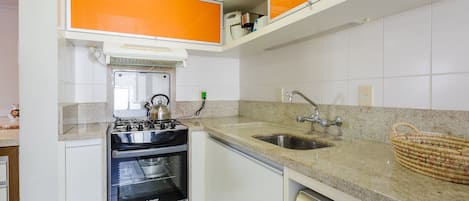 A kitchen with white cabinets, an oven, a sink, and a dishwasher.