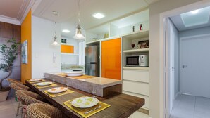 A modern kitchen with a central island, built-in appliances, and a dining area with wicker chairs. - Comfortable Beachside Apartment in Floripa Rvg101 (Florianópolis)