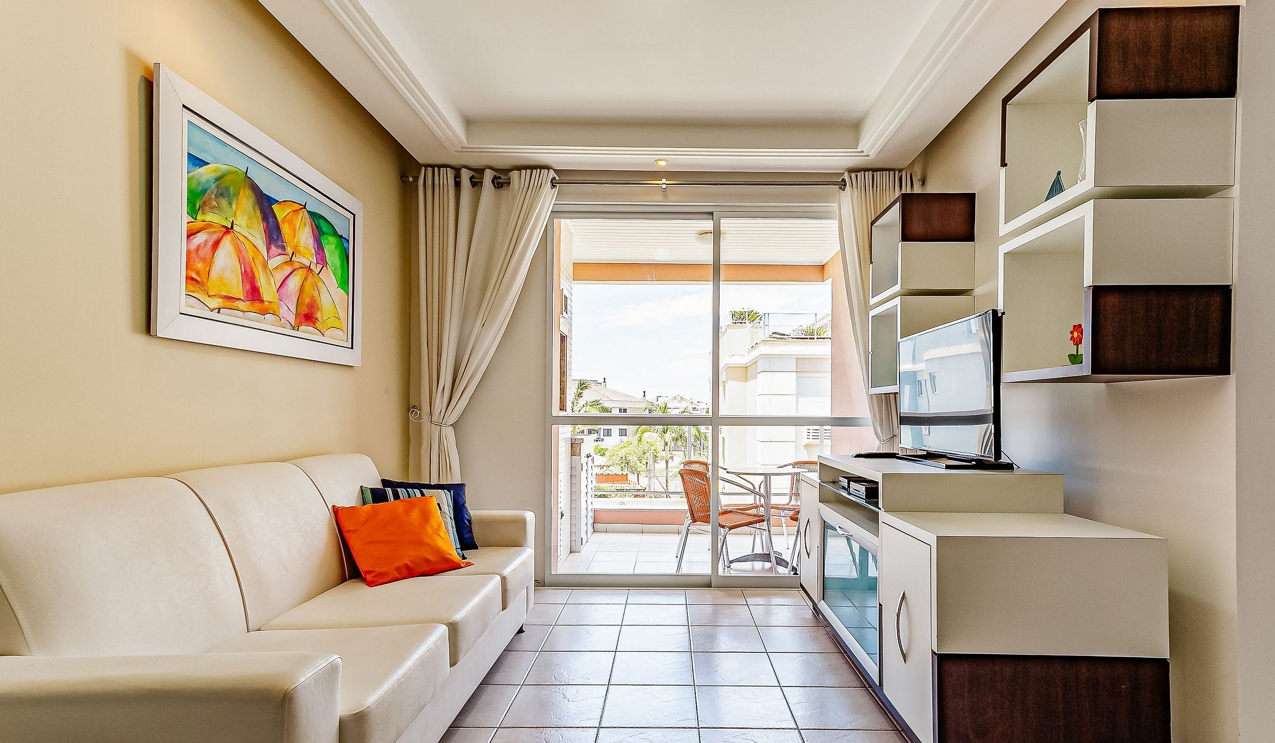 Un espacio habitable compacto con un sofá, un televisor y un cuadro en la pared.
