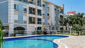 Un immeuble résidentiel à plusieurs étages doté d’une piscine, de balcons et offrant une vue sur un ciel dégagé.