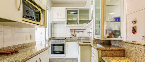 A narrow kitchen with white cabinets, a built-in oven, and a microwave.