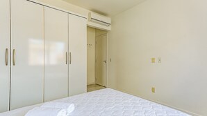 Une chambre à coucher comprenant un lit, une armoire et un appareil de climatisation.