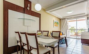 A dining area with a table set for four, surrounded by wooden chairs. There is a wall-mounted light fixture above the table and a painting on the wall. - Comfortable Apartment 50m From the Beach Rvg208 (Florianópolis)