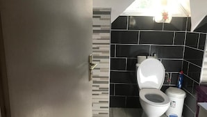 Ein Badezimmer mit Toilette, Mülleimer und Wand mit Schwarz-Weiß-Fliesenmuster.