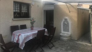 Eine Terrasse im Freien mit Tisch, Stühlen, einem Blumentopf und einer Zierbrunnen.