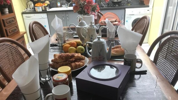 Ein Frühstückstisch mit Teekanne, Tassen, einer Tasse und einem Teller mit Croissants.