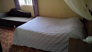 Ein Zimmer mit einem Bett, einem Sofa, einem Fenster mit Vorhängen und Holzboden.