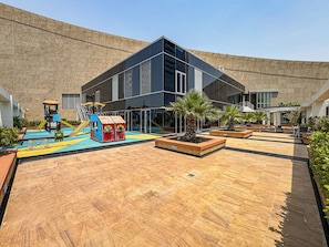 A courtyard with a play area, seating, and potted plants. - Amazing DIFC Studio, 9 Min to Burj Khalifa (Dubai)