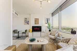 A modern living room with a flat-screen TV, a coffee table, and a sofa. - Amazing DIFC Studio, 9 Min to Burj Khalifa (Dubai)