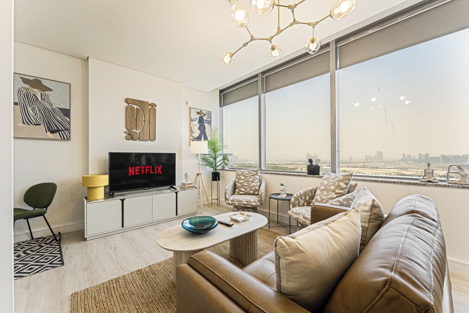 A modern living room with a large window, a flat-screen TV, and a sofa.