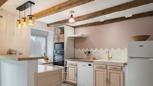 A kitchen with wooden beams, a built-in oven, a dishwasher, and a white refrigerator. - La Maison de Gautro – Holiday Home with Terrace and Garden (Tréhorenteuc)