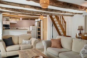 A cozy living room with two sofas, a coffee table, and a kitchen in the background.