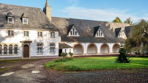 A historic building with a central courtyard, arched walkways, and a prominent tower. - La Maison de Gautro – Holiday Home with Terrace and Garden (Tréhorenteuc)