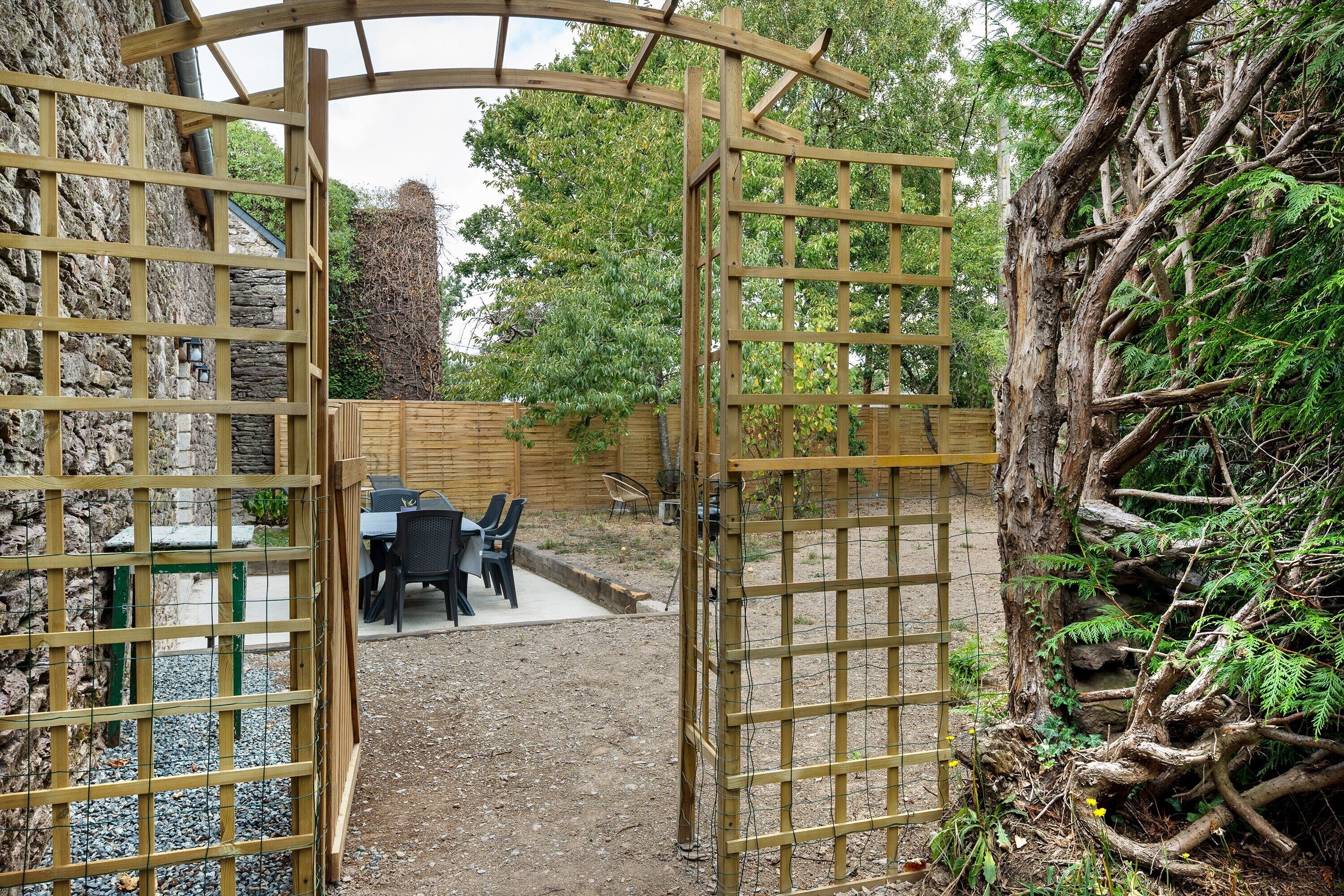 A wooden gate leading to a patio area with a table and chairs.