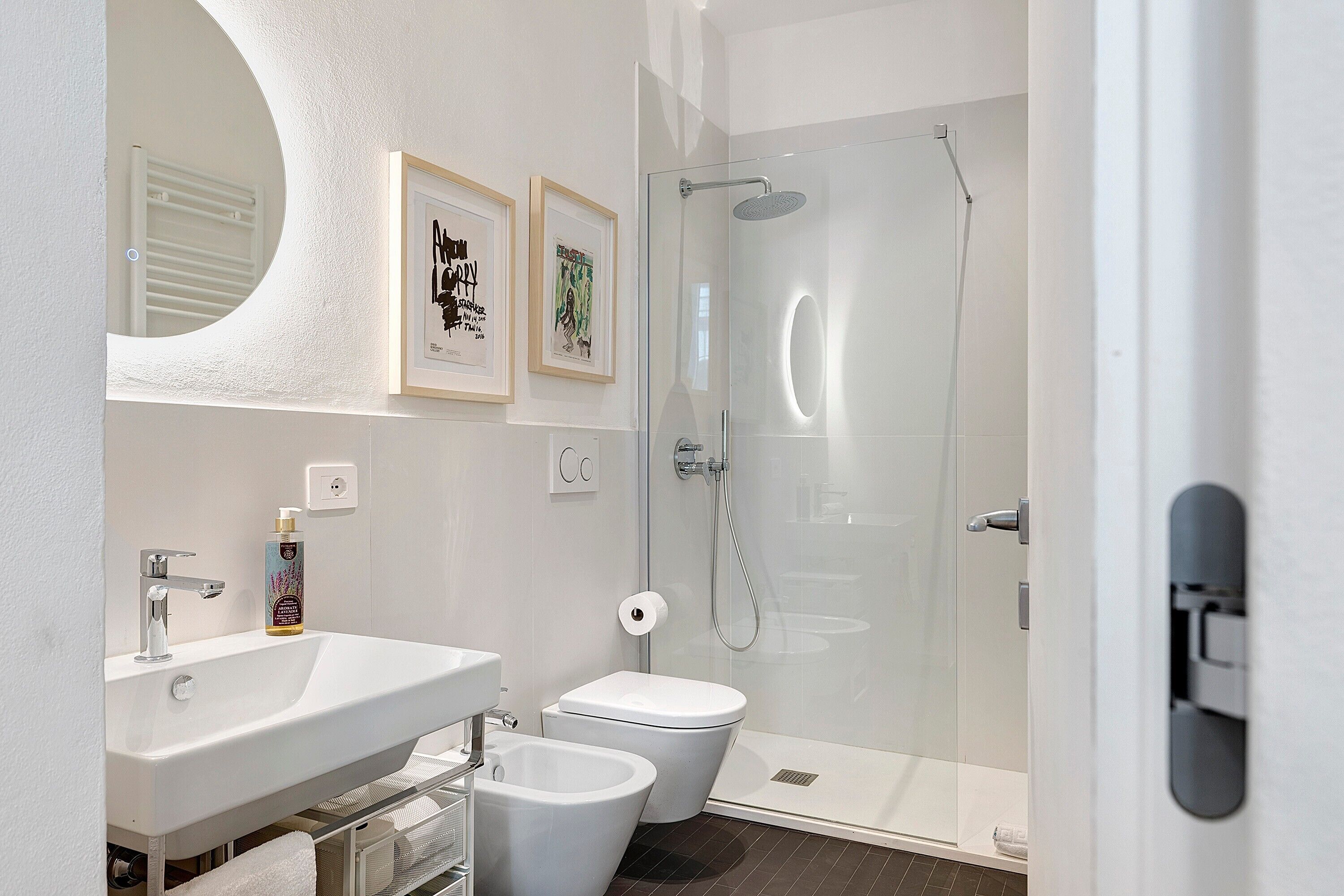 Een moderne badkamer met een douchecabine van glas, een witte wastafel en een toilet.